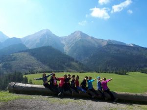 Glückliche Wanderer, die auf einem Baumstamm mit Tatra Bergen im Hintergrund sitzen